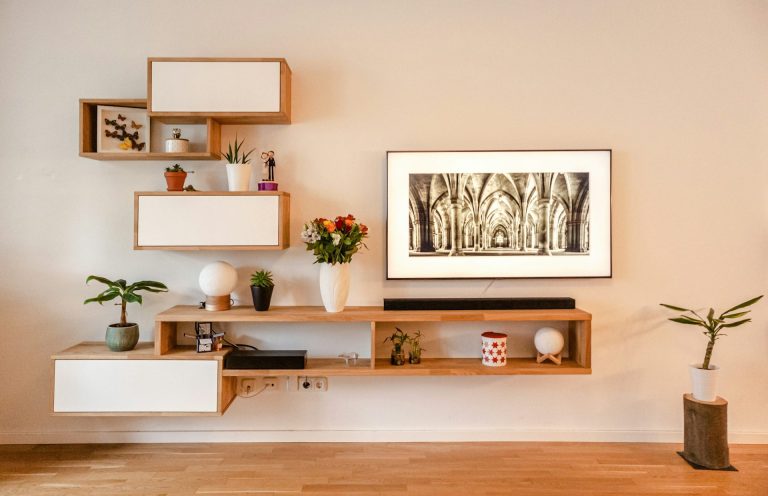 Mueble de pared moderno con estantes, planta, flores y cuadro en un ambiente minimalista.